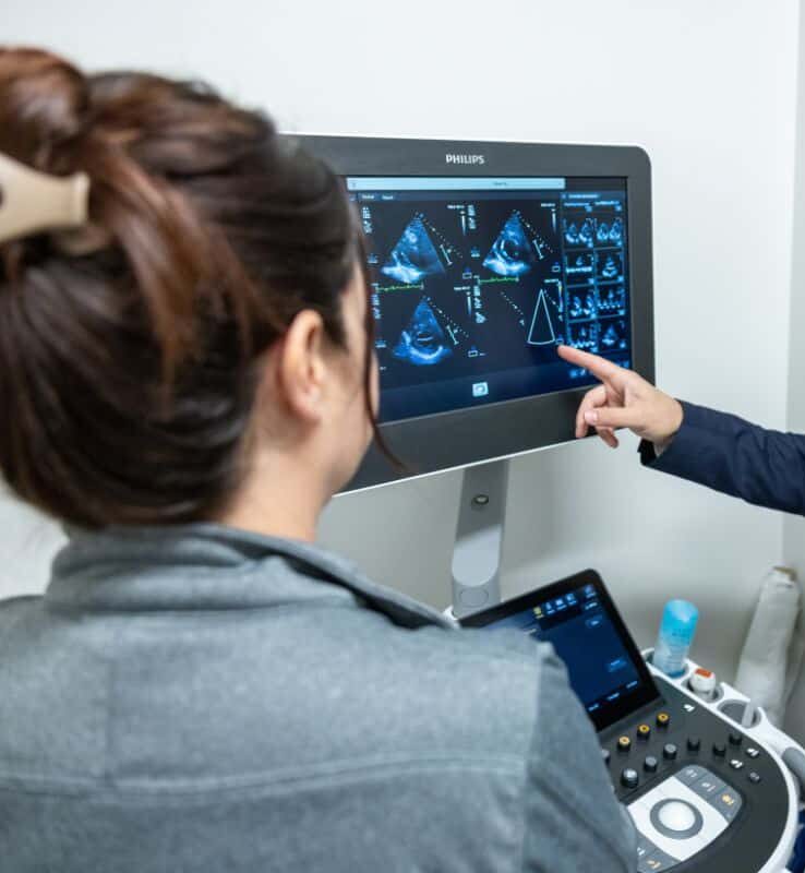 Male doctor pointing at diagnostic screen while discussing results with female colleague at Oracle Heart and Vascular