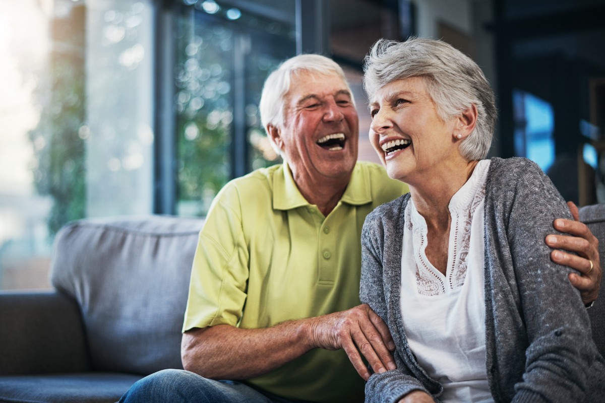 Expert-heart-rhythm-disorders-treatment-king-george Happy senior couple laughing together on sofa at home, enjoying life and heart health.