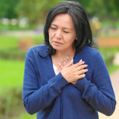 Woman holding her chest, looking concerned, representing heart disease and preventative cardiology