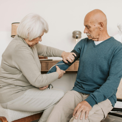 Older woman checking older man's blood pressure, representing how to manage high blood pressure