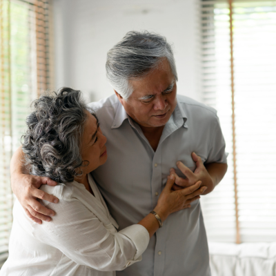 Older man holding his chest while his wife comforts him, representing early heart attack warning signs